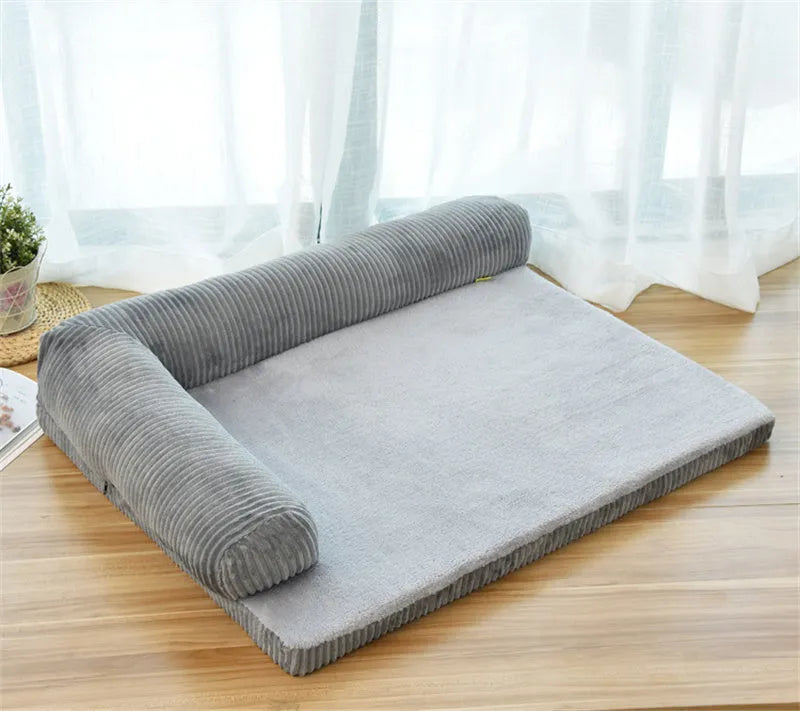 A large grey corduroy dog sofa bed with bilateral sides and a non-slip base on a wooden floor.