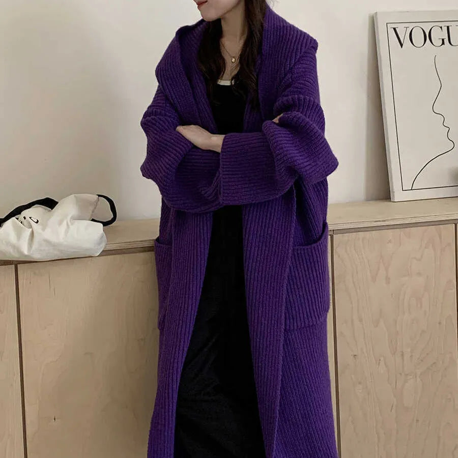 Woman wearing a loose beige hooded zip-front cardigan coat with raglan sleeves.