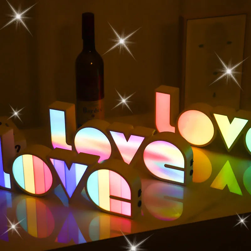 Rainbow coloured plastic LED LOVE light decoration on a desk.