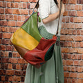Brown cowhide leather crossbody travel bag with stitching, shown holding a laptop and A4 magazine.