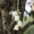 Green and white knitted wool car plant decoration with 25cm hanging rope on a car dashboard