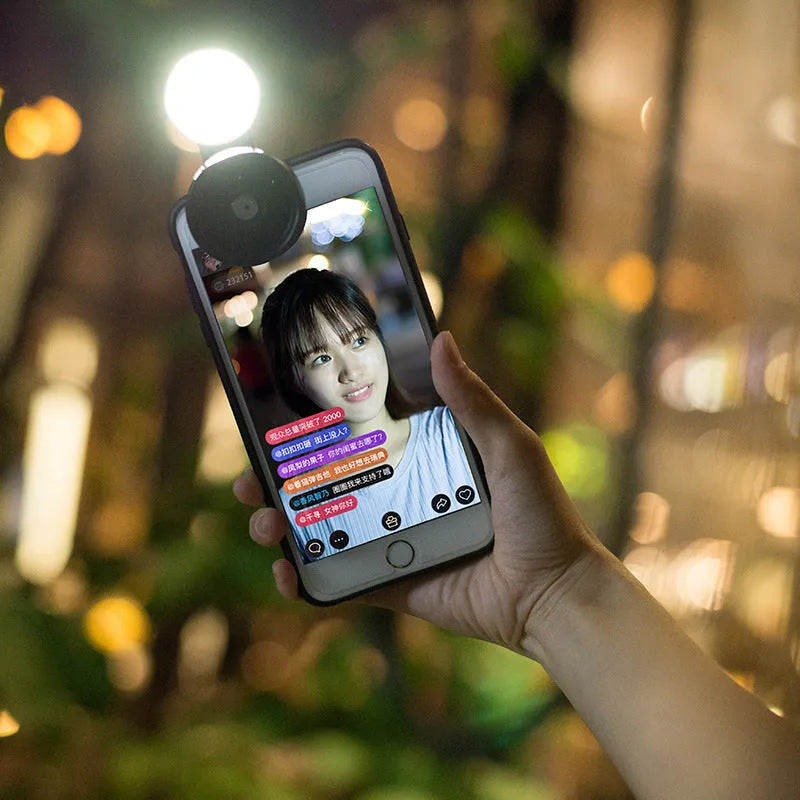 Universal smartphone camera lens attachment kit with wide-angle, macro, and fisheye lenses, LED lights, and a tripod grip.