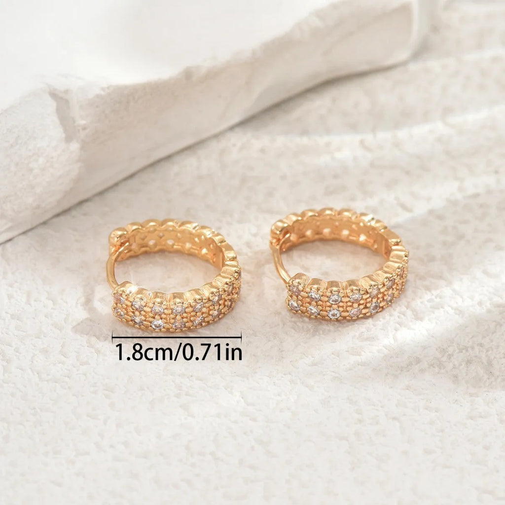 A pair of copper geometric pattern ear studs with round, dot, and ring design elements.