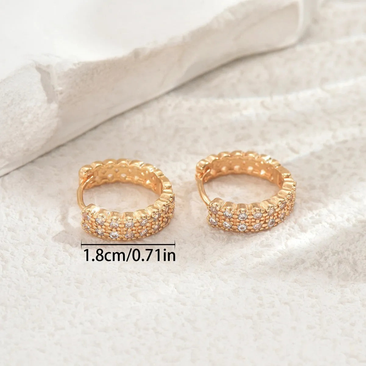A pair of copper geometric pattern ear studs with round, dot, and ring design elements.