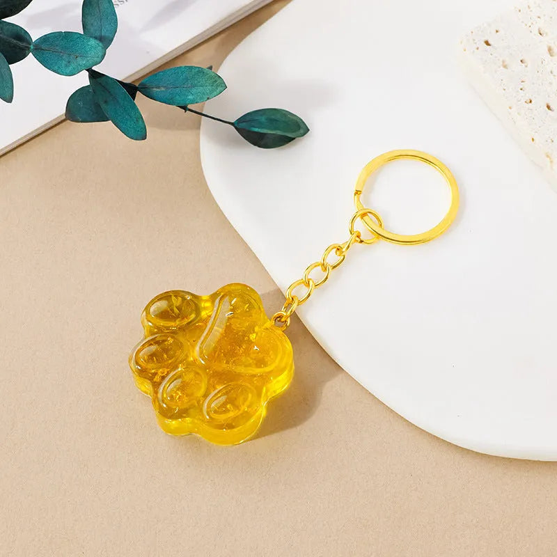 Small natural crystal cat's paw shaped pendant on a keychain ring, shown in various crystal colour options.