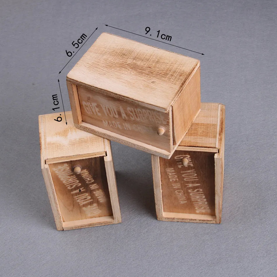 Wooden prank scare box open showing a lifelike spider figurine on a spring, next to the box lid.
