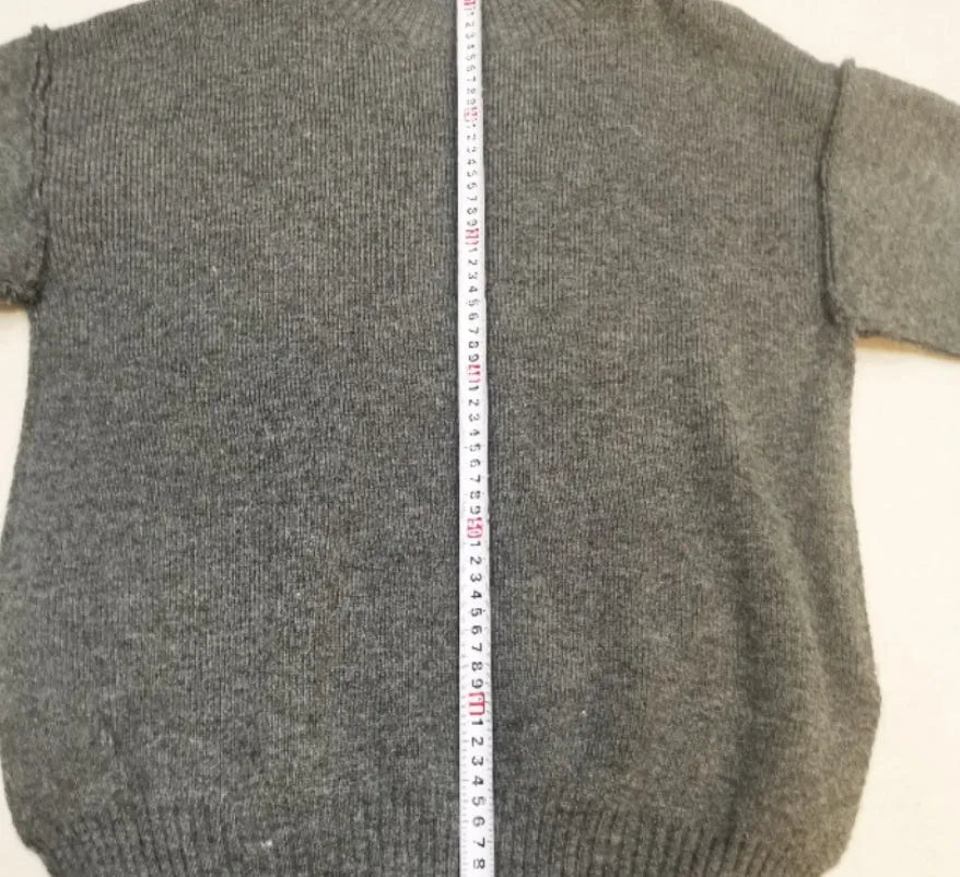Women's dark grey acrylic knit sweater suit with side-slit top and matching trousers.