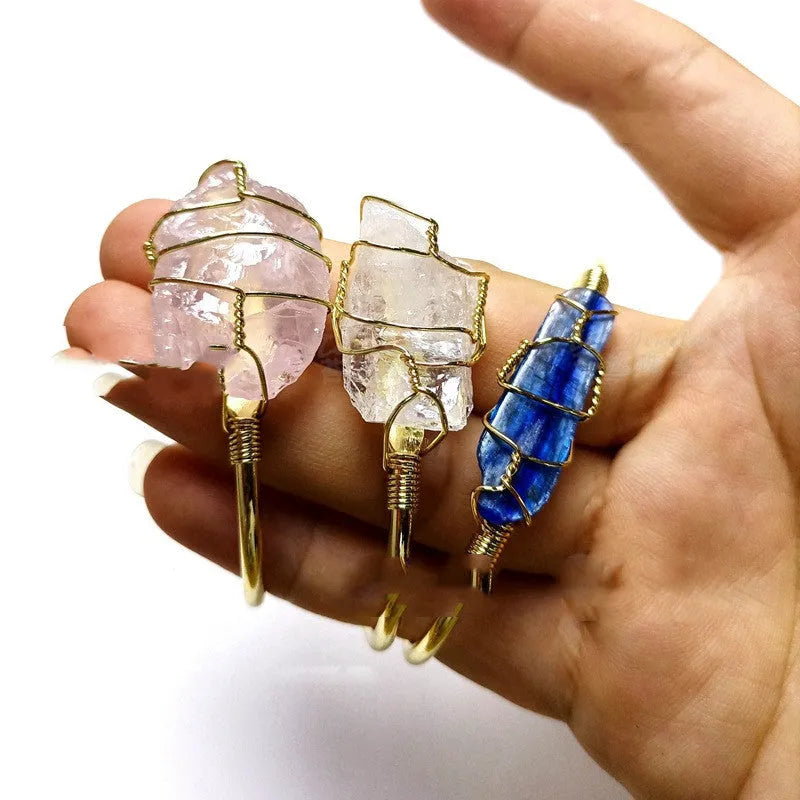 Natural rough stone crystal bracelet with gold geometric winding on a wrist.