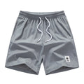 Man wearing grey straight-cut elastic drawstring summer shorts on a beach.