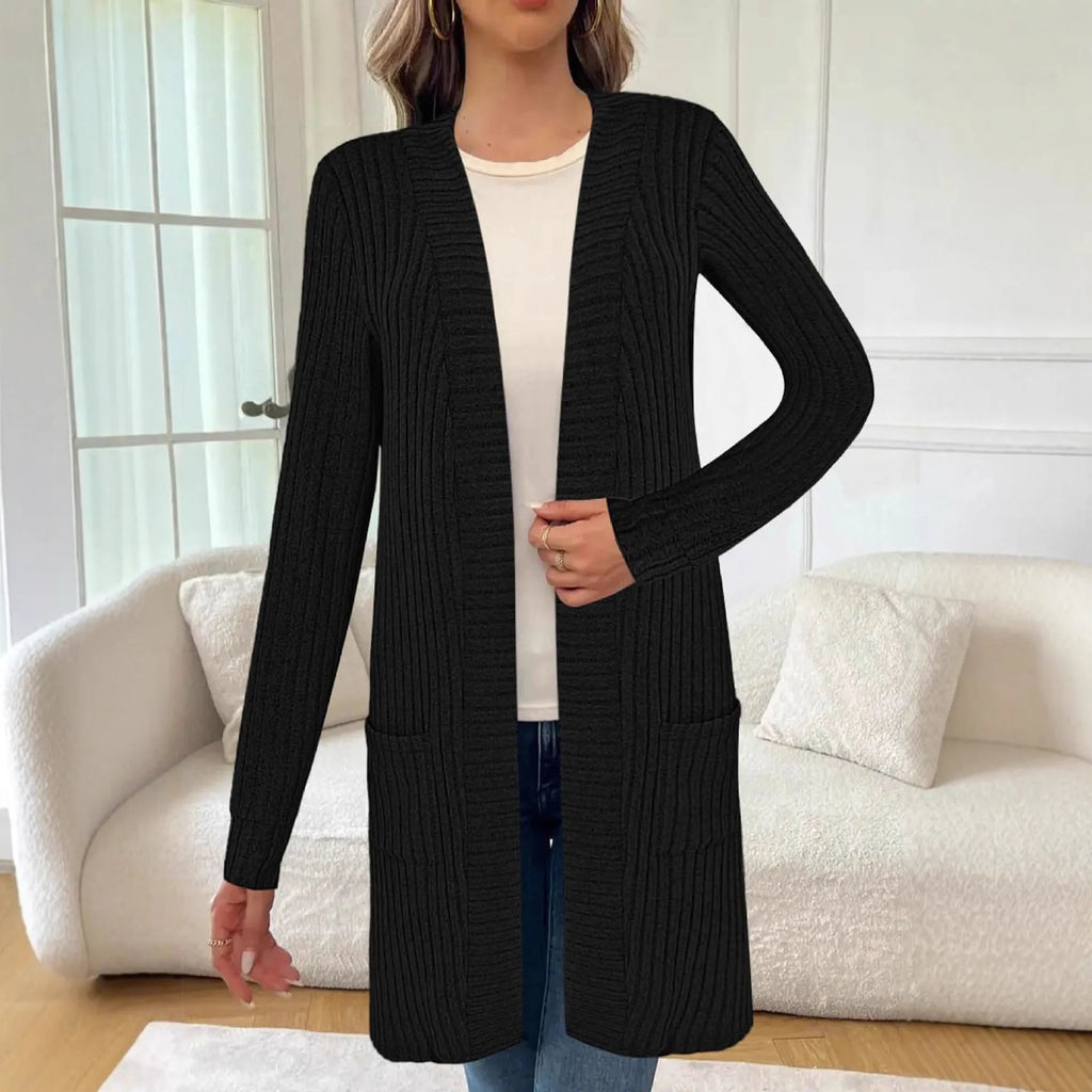 A woman wearing a loose grey knitted cardigan jacket with long sleeves and patch pockets.