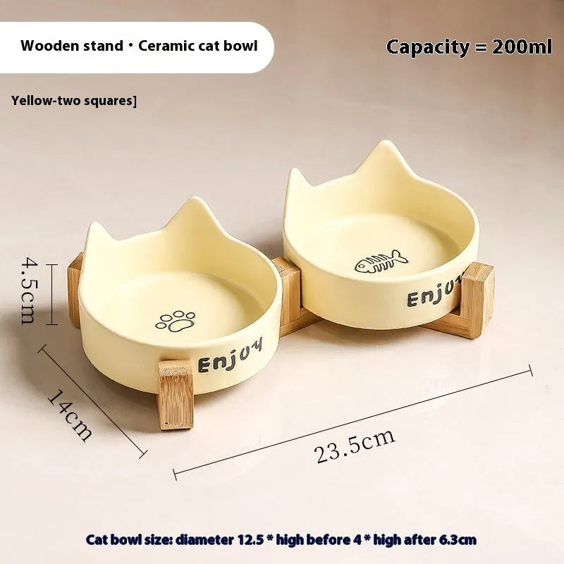 Porcelain cat bowl with cat ear handles in a wooden anti-tumble frame, showing paw print design.