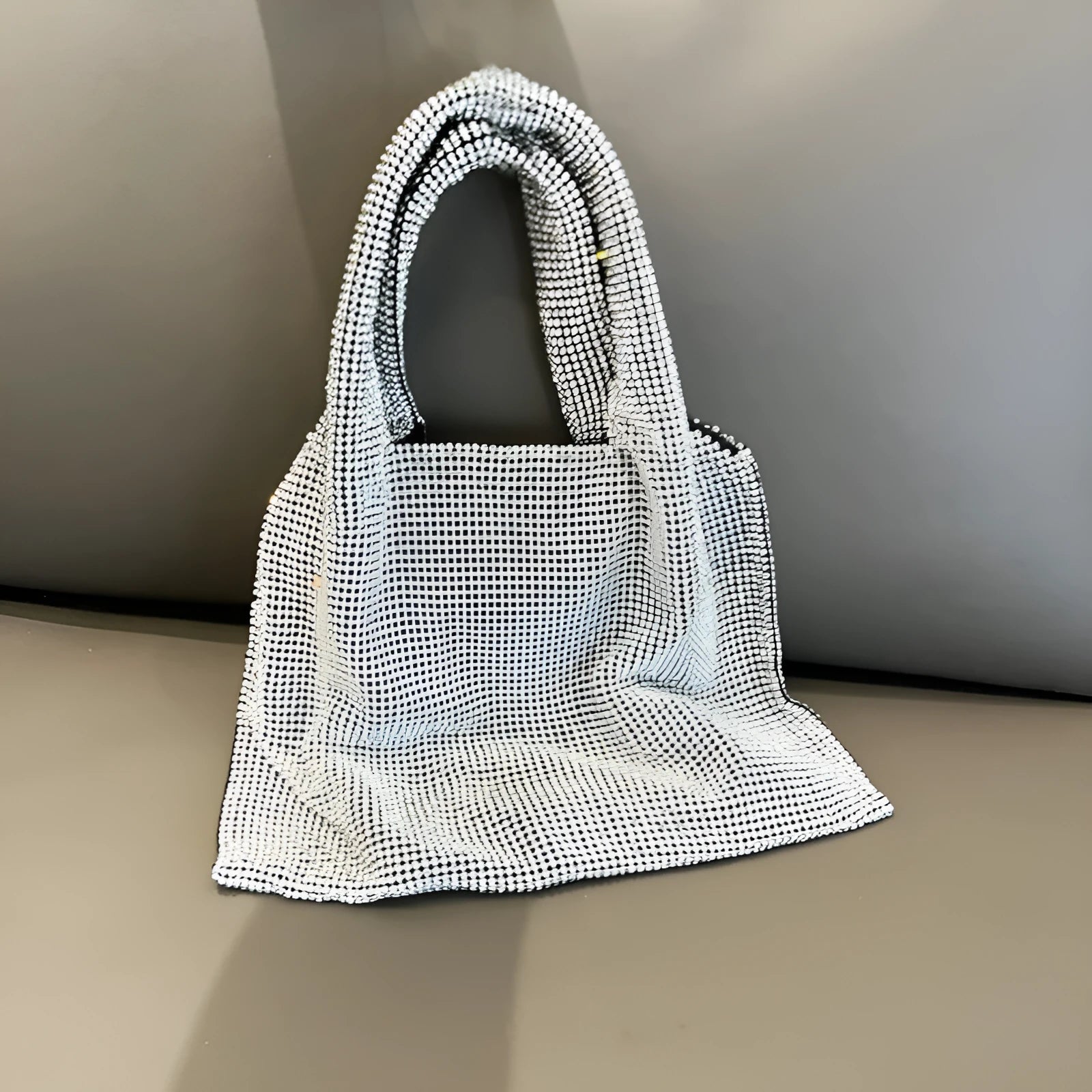Silver handbag decorated with shiny rhinestones, made from cotton thread with one open pocket.