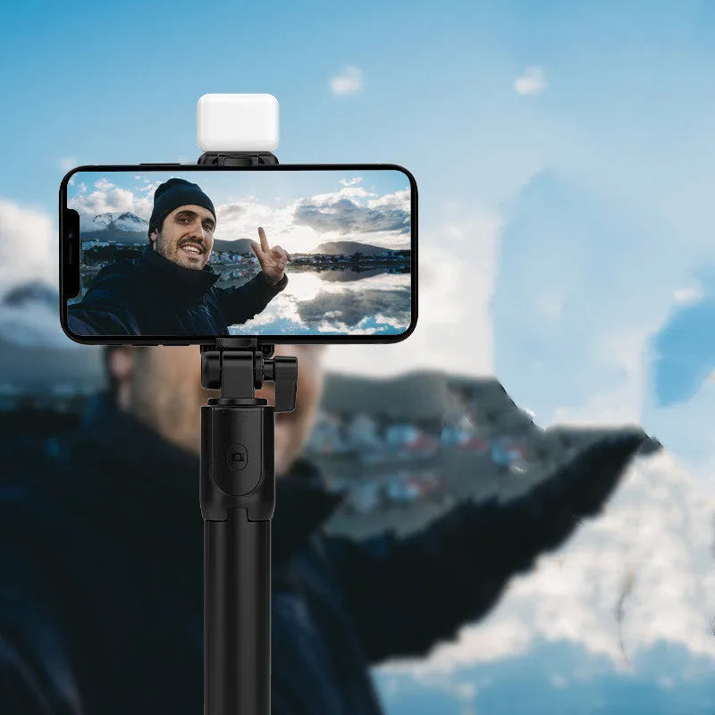 Black Bluetooth selfie stick with extended tripod legs holding a smartphone.
