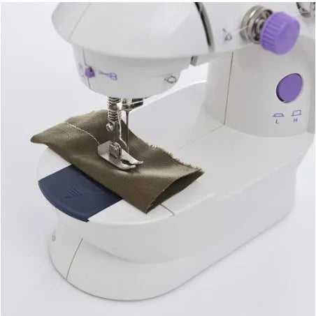Miniature white and grey electric household sewing machine with thread spool and power cord.