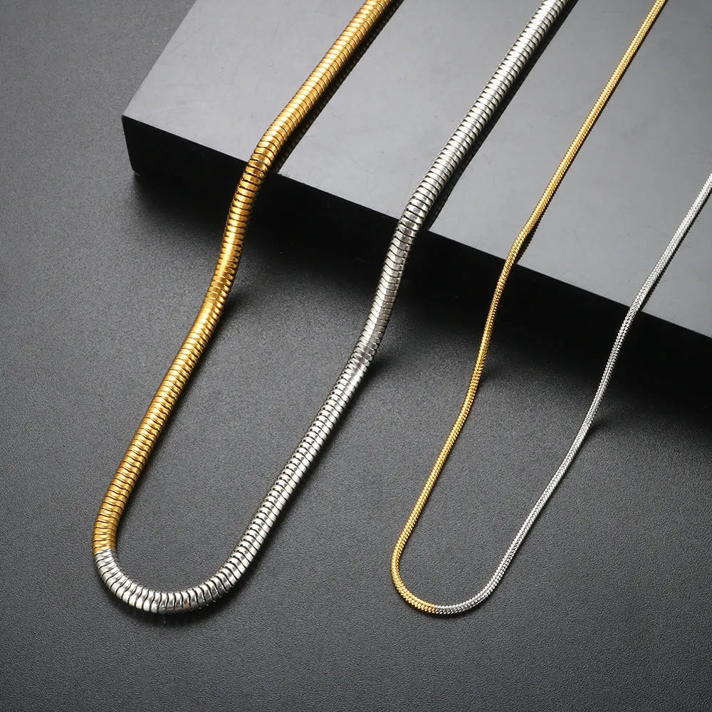 Close-up of a woman's golden 3mm wide snake bones chain necklace with geometric links.