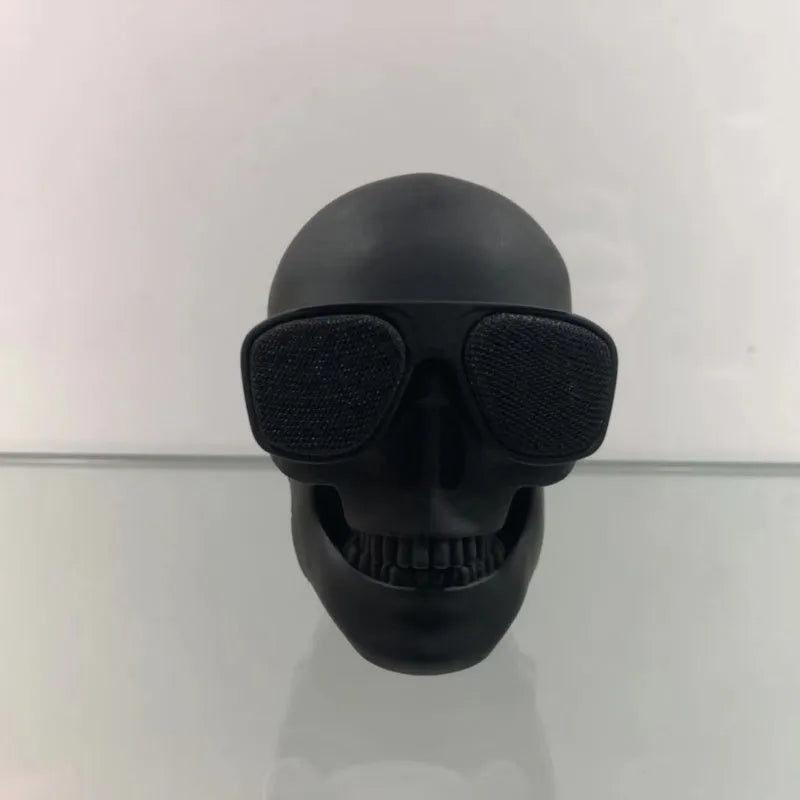 Small skull-shaped wireless Bluetooth speaker in black, portable with button controls and USB charging