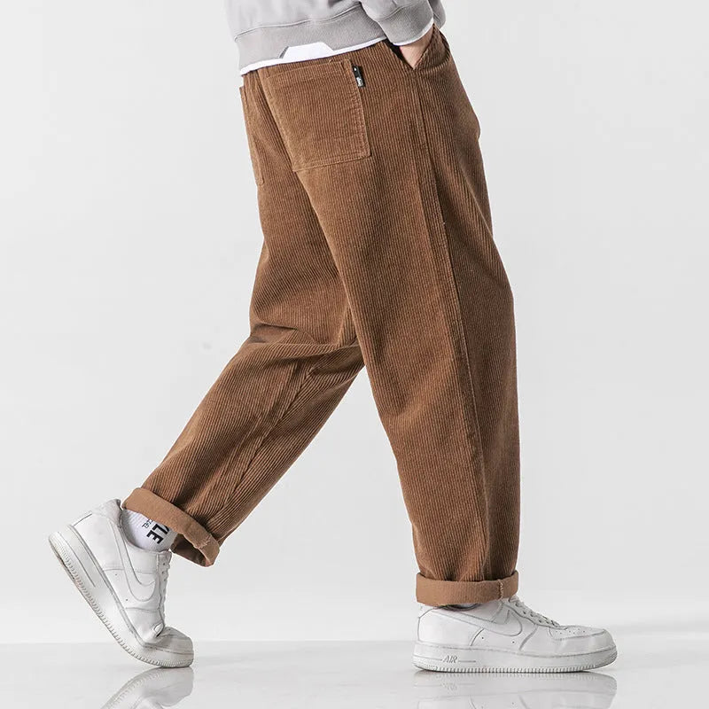 Men's loose straight corduroy sports trousers in Army Green on a grey background.