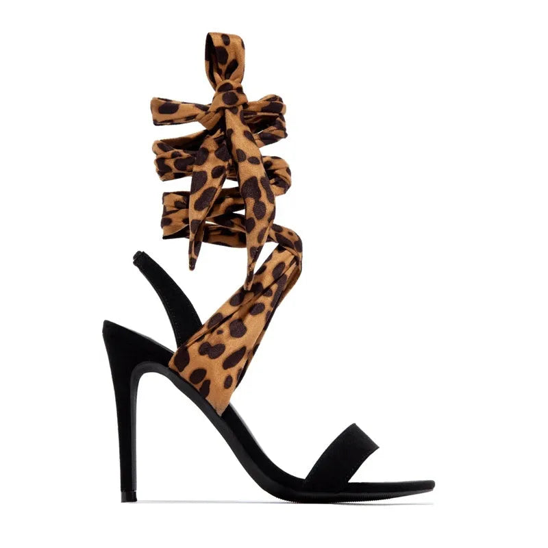 Light brown leopard print women's high-heeled sandals with cross-straps and a tall slender heel.