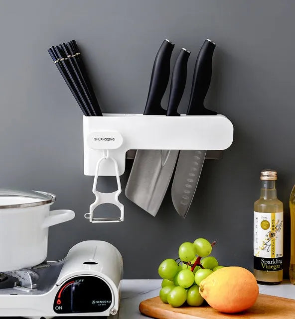White plastic wall-mounted magnetic knife rack holding several kitchen knives