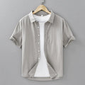 Men's light grey loose fit short-sleeved cotton cardigan shirt on a hanger.