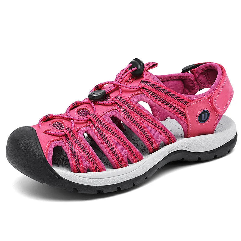 Women's black leather mesh toe box sandals with elastic band and rubber sole on a beach