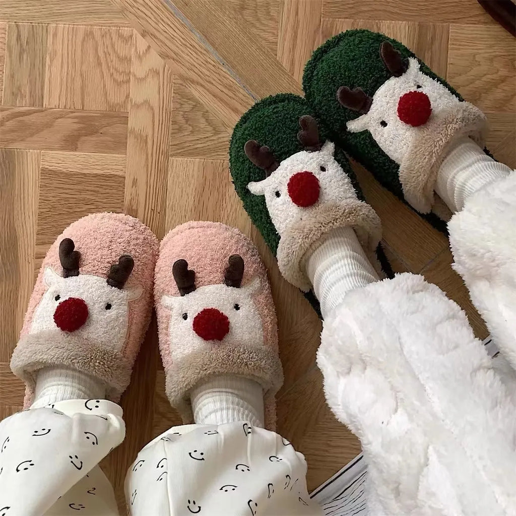 Women's brown Christmas elk plush slippers with non-slip PVC sole on a wooden floor.