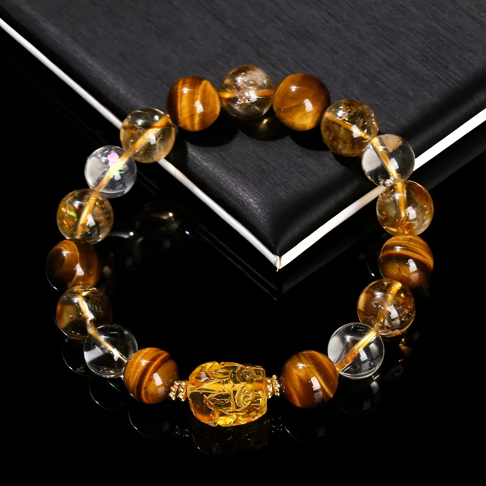 Close-up of a unisex bracelet with 10mm yellow tiger's eye and citrine round beads and a detailed beeswax pi xiu charm.