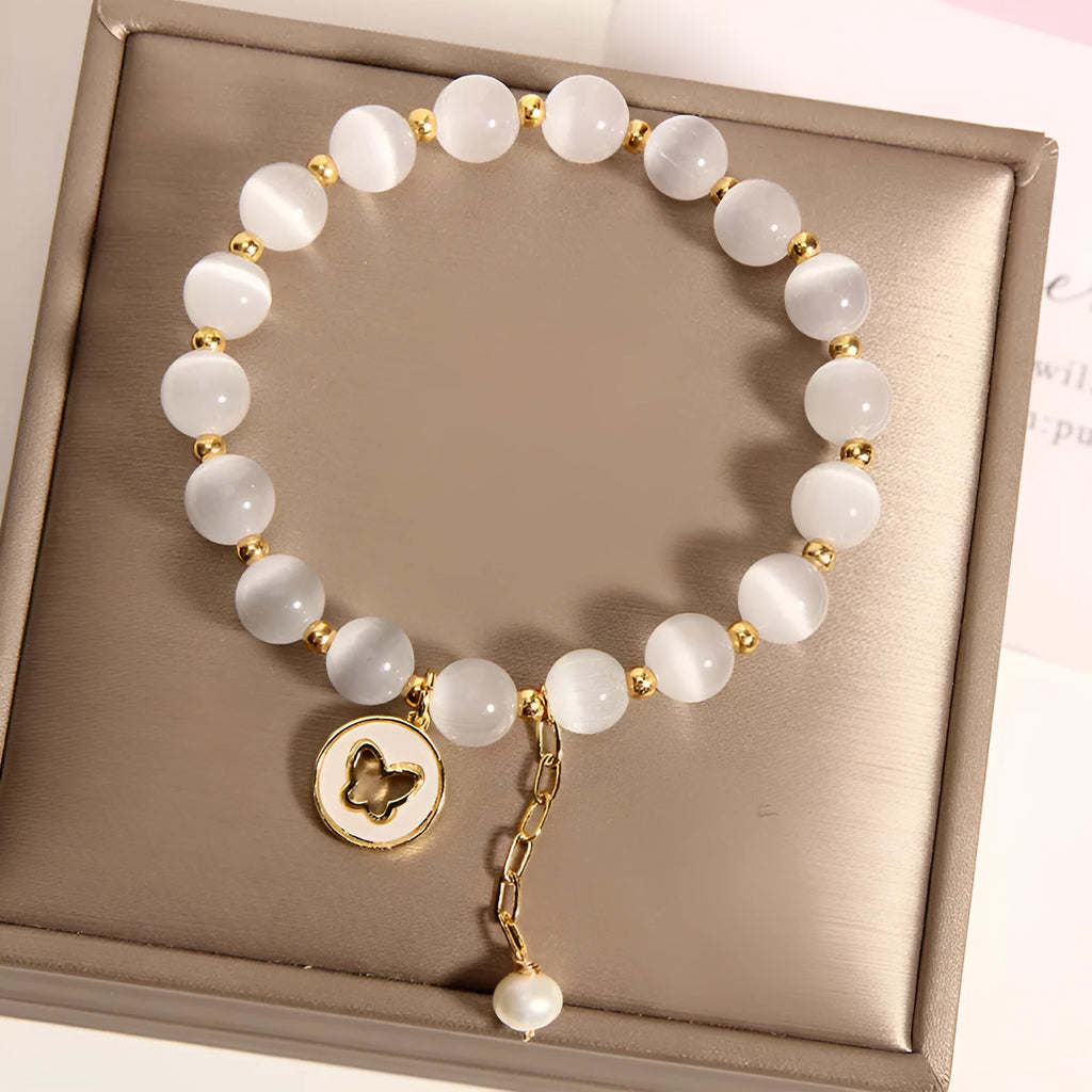 Close-up of a white cat's eye crystal bracelet with geometric links on a wrist.