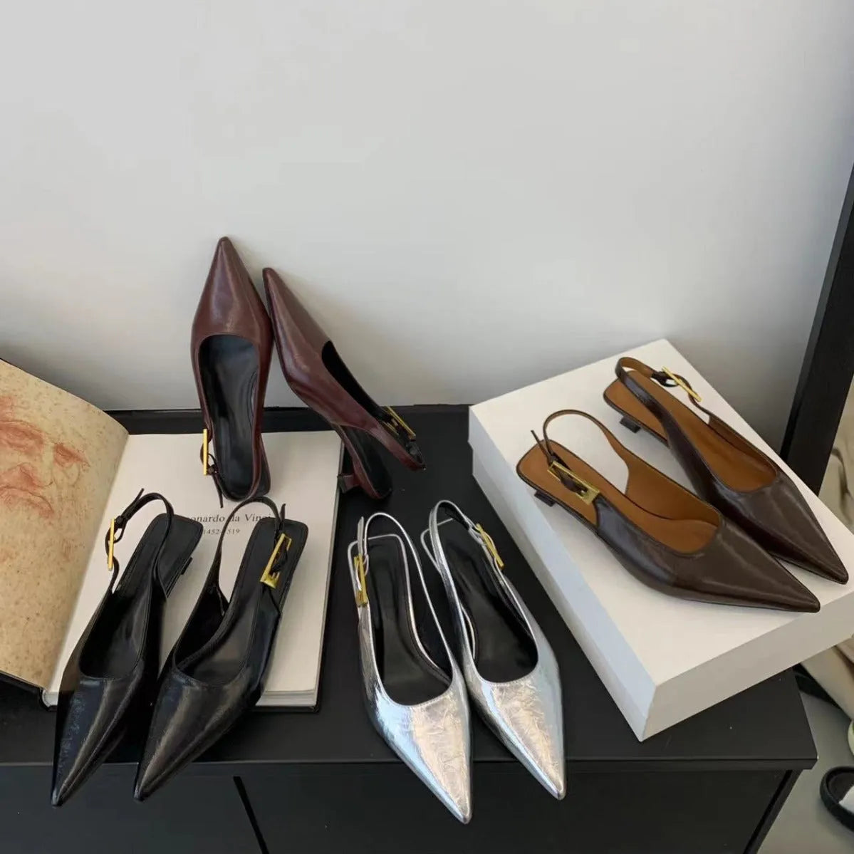 Women's black pointed leather low-heel shoes with thin decorative straps and a rubber sole.