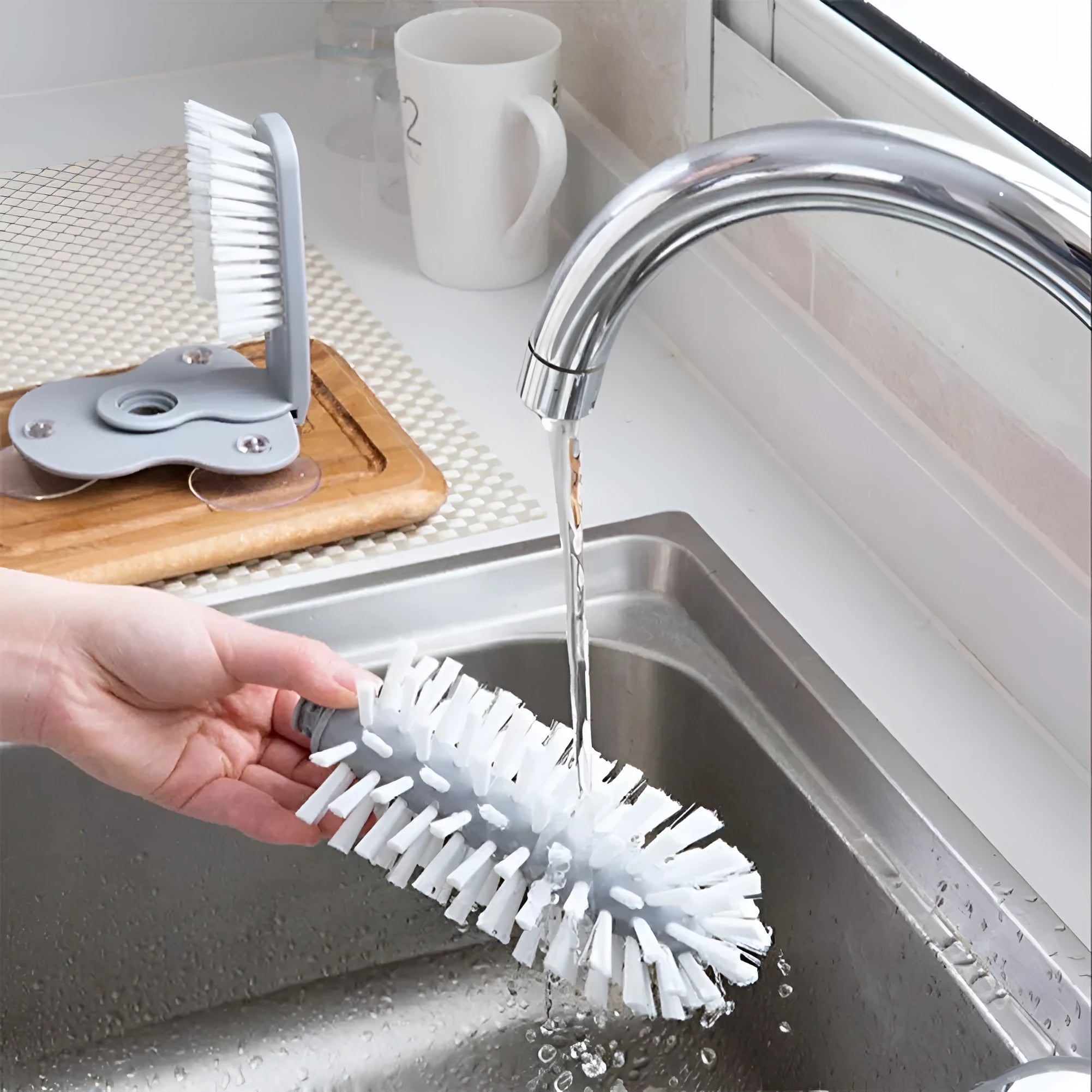 Grey 2-in-1 cup scrubber with double-sided bristles and three suction cups on a white surface