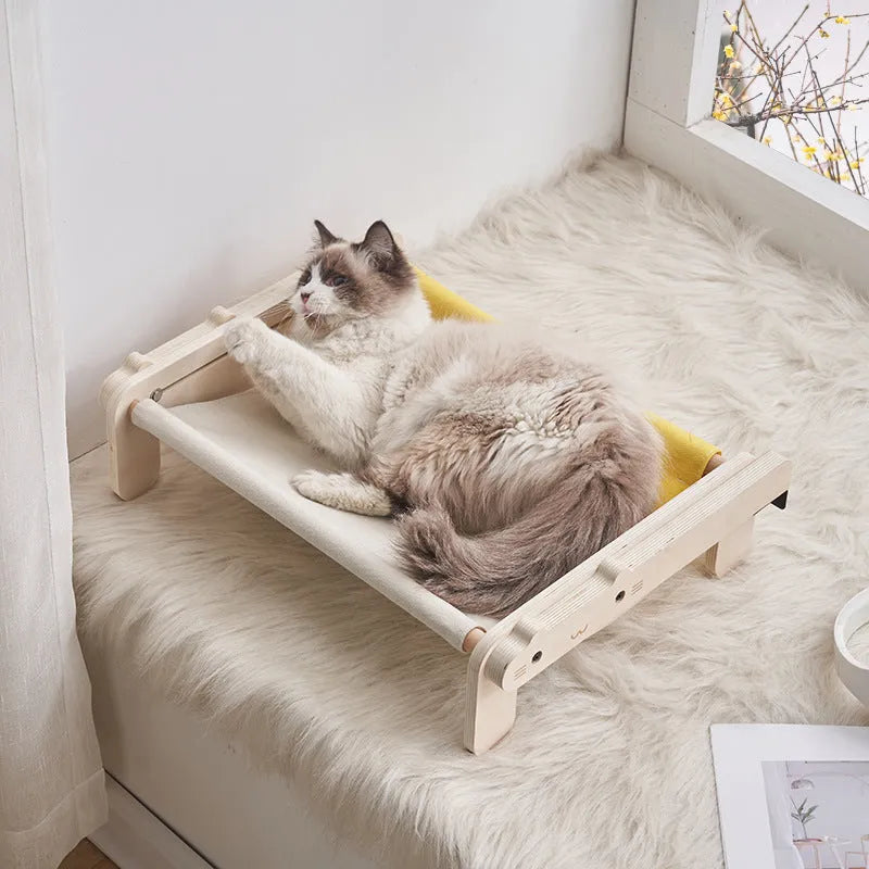 Solid wood cat bed with a removable patterned cover on a wooden floor