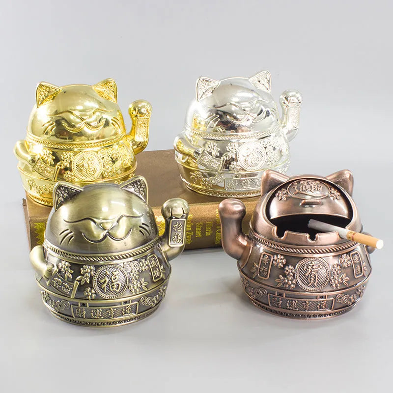Zinc alloy Lucky Cat ashtray with cover in a gold-black finish on a table