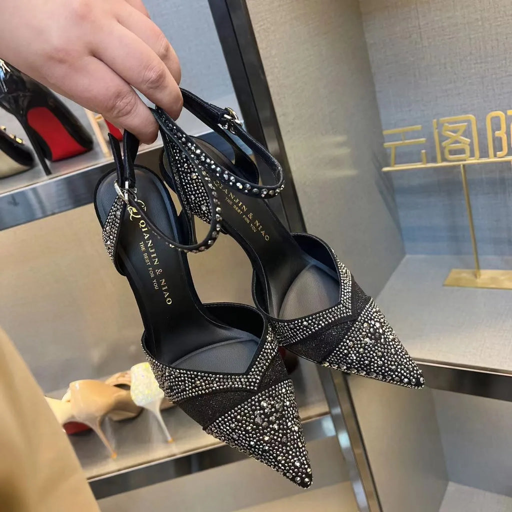 Women's black pointed toe stiletto heels with a hollow design and red sole.