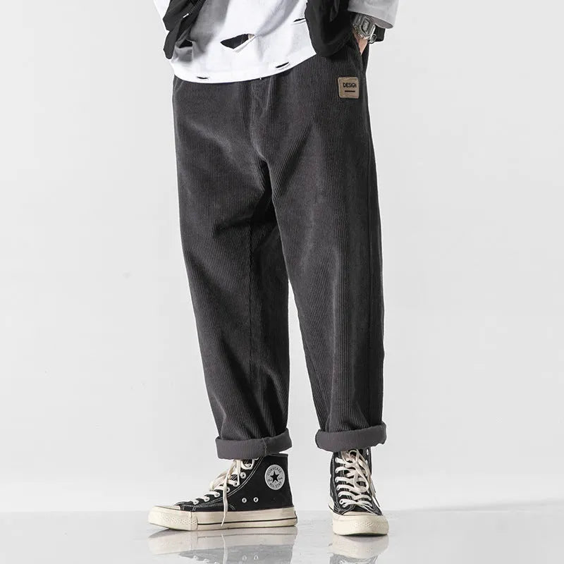 Men's loose straight corduroy sports trousers in Army Green on a grey background.
