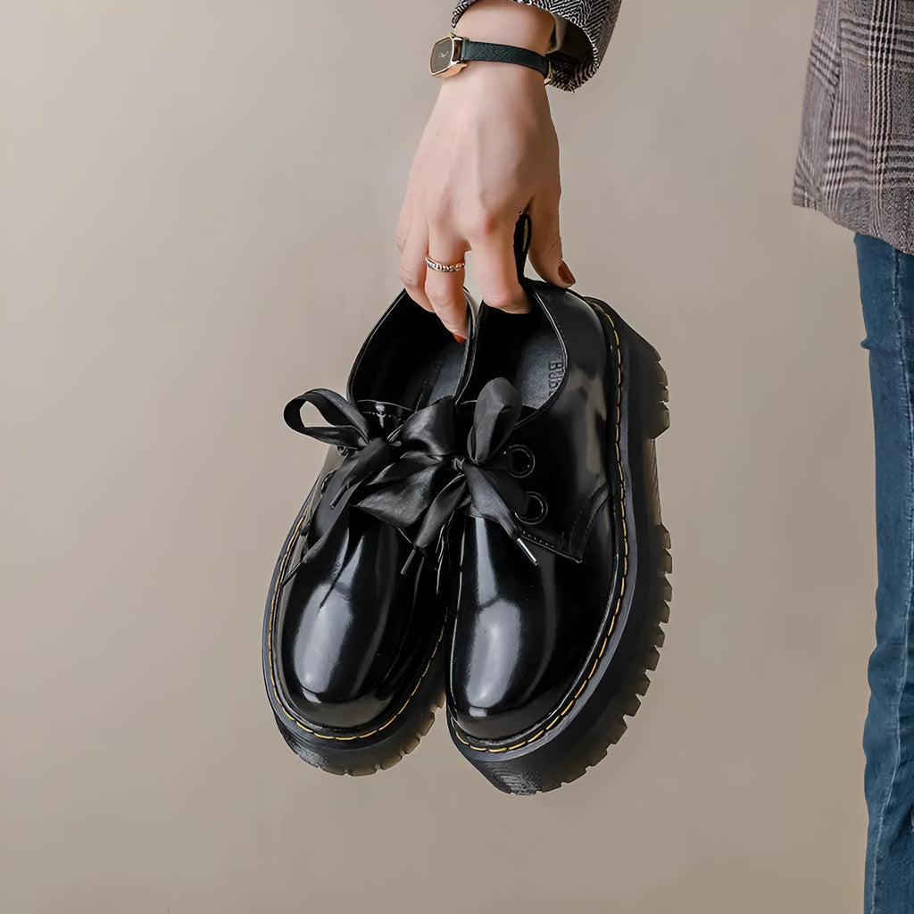Black thick soled women's lace-up shoes with ribbon and cross strap details on superfine fibre upper