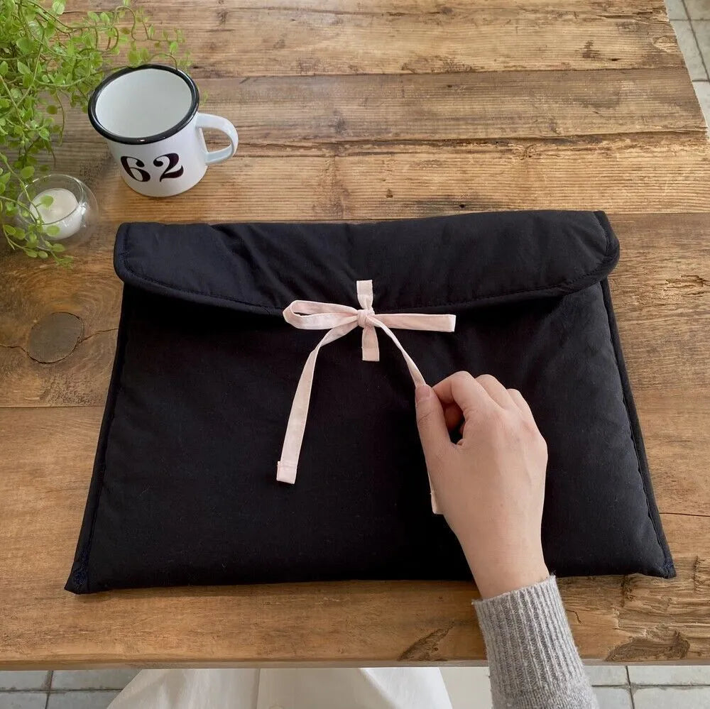 Black and white quilted laptop bag with a large ballet-style bow on the front.