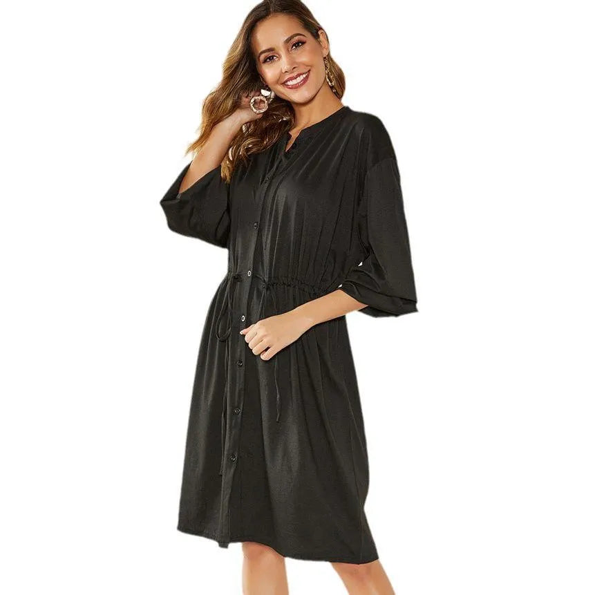 A woman wearing a red mid-length A-line cardigan dress with an elasticated waist and long sleeves.