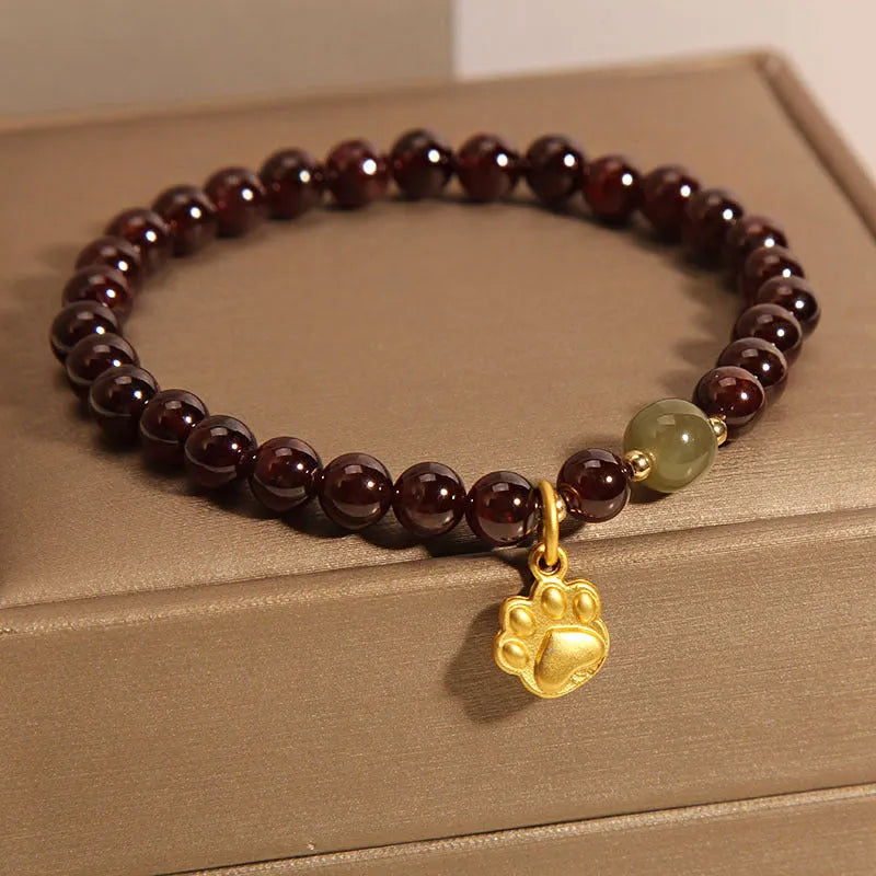 Women's crystal bracelet with a cat's paw garnet design on a polished metal setting.