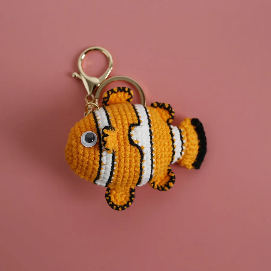 Crocheted wool fish keychain in cartoon ugly fish doll style with key ring, shown in orange, blue or pink