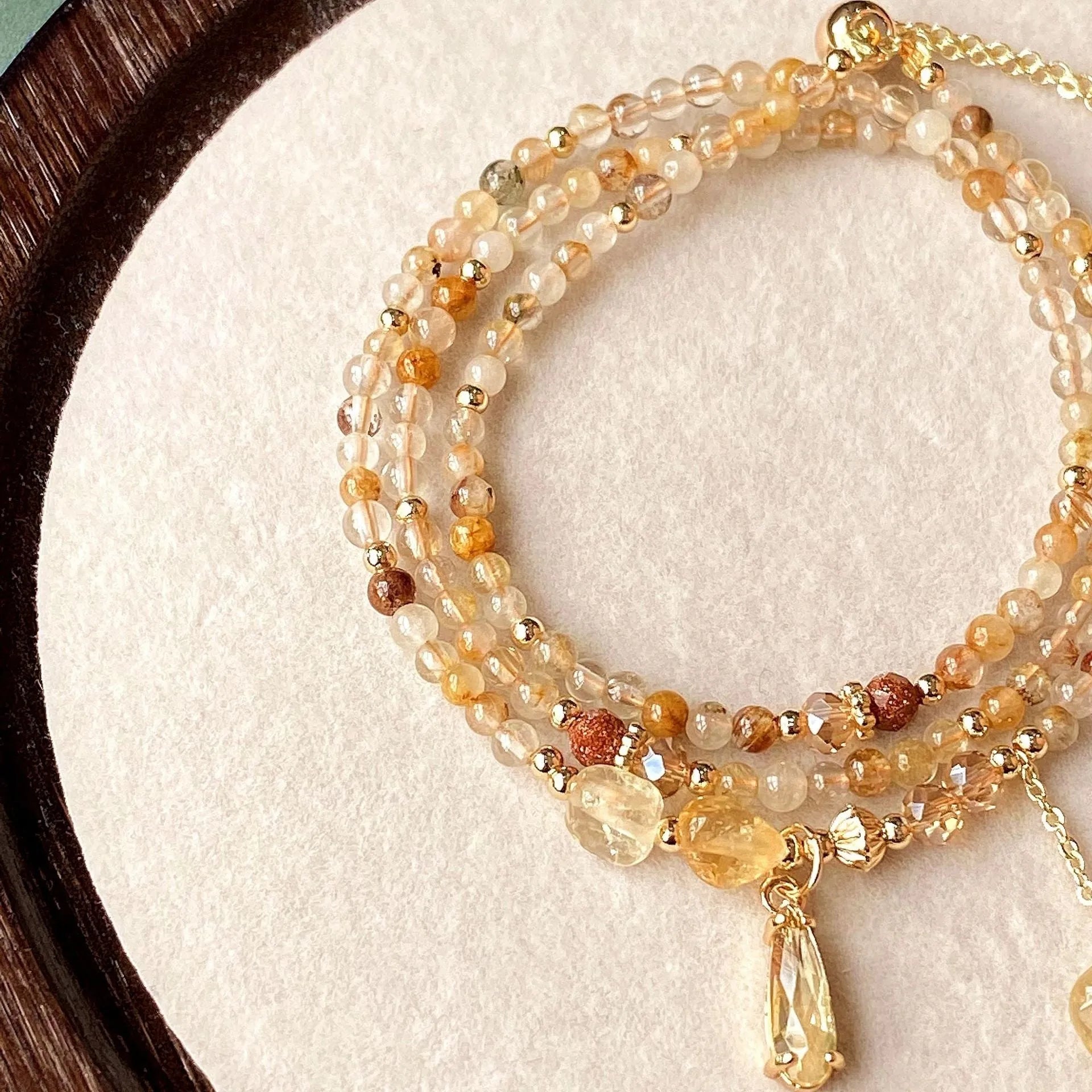 Gold electroplated bracelet with three circles of caramel citrine and a Saturn charm.