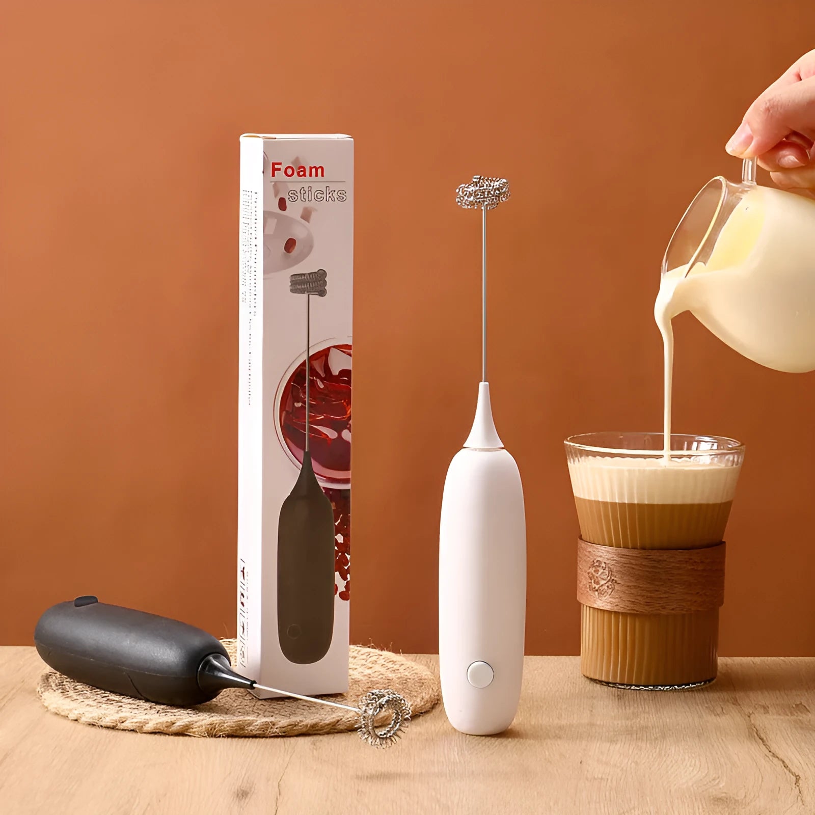 Electric hand-held milk frother blender in black and white colour options on a kitchen counter.
