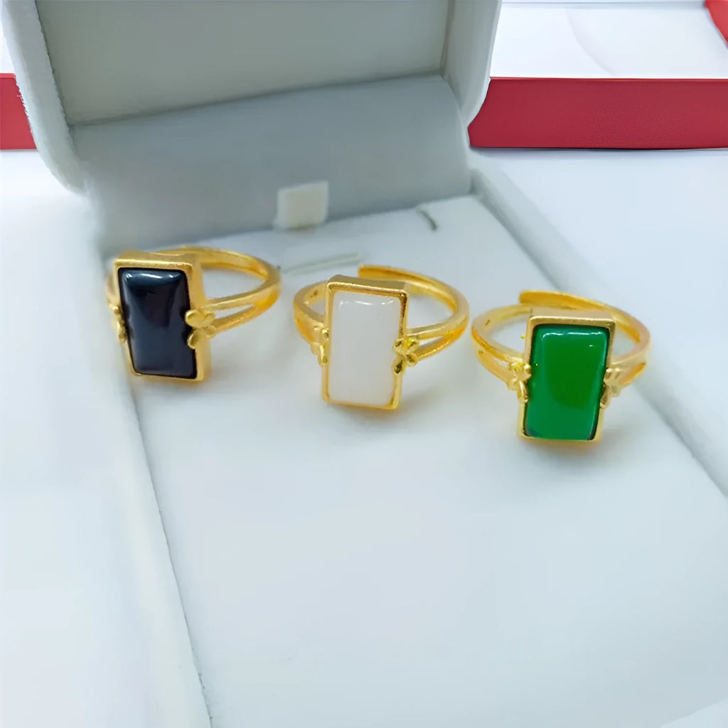 A gold-plated brass ring with an adjustable band and a central green artificial gemstone, in a national style.