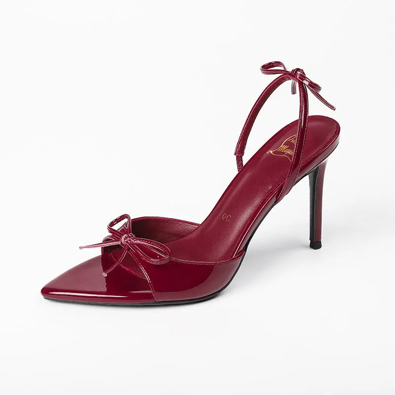 Women's black pointed stiletto high heels with open toe and ankle strap buckle on a white background.