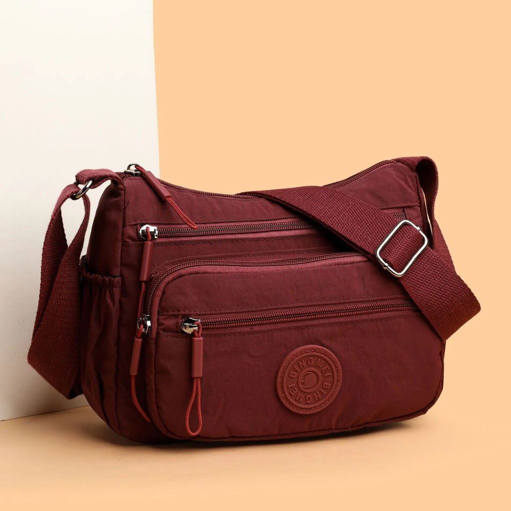 Water-repellent nylon crossbody cloth bag in black, grey or red with internal zipper compartments