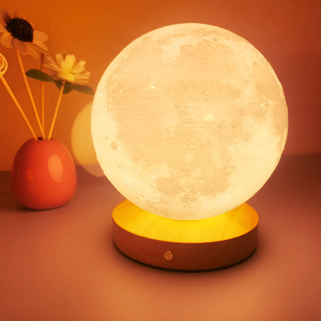 Rotating sleeping moon night lamp on wooden base showing three-colour light options.