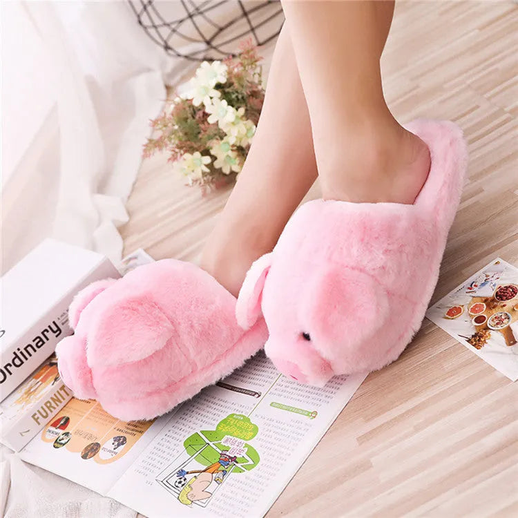 Pink pig-shaped plush floor slippers on a white background.
