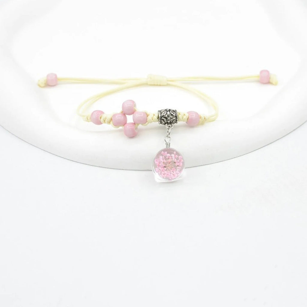 Close-up of a hand-woven glass dried flower bracelet with large colourful beads on a wrist.