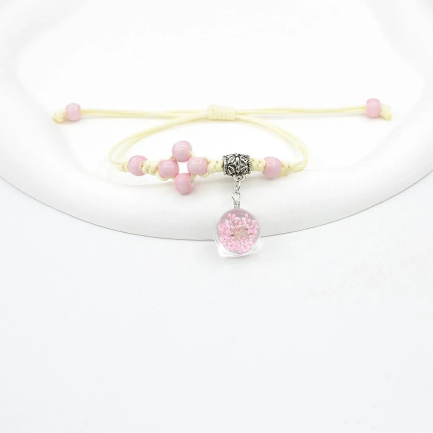 Close-up of a hand-woven glass dried flower bracelet with large colourful beads on a wrist.