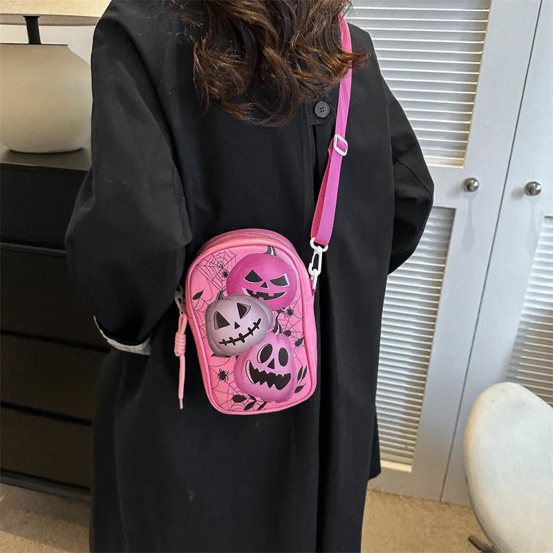Black mini crossbody bag with Halloween graffiti print of cartoon pumpkins and bats.