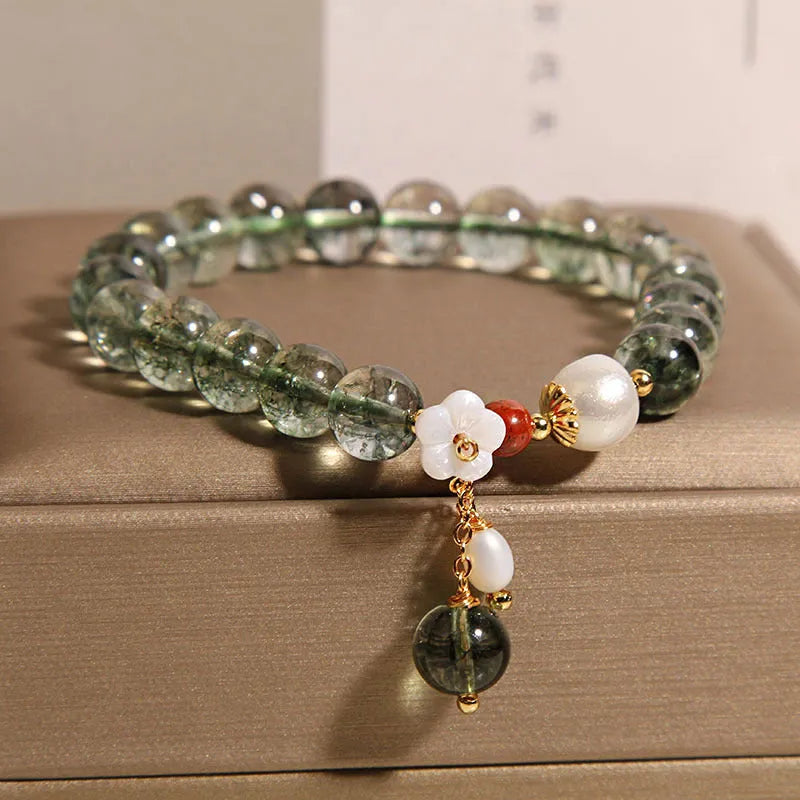 Green phantom quartz crystal bracelet with shell flower charms on wrist